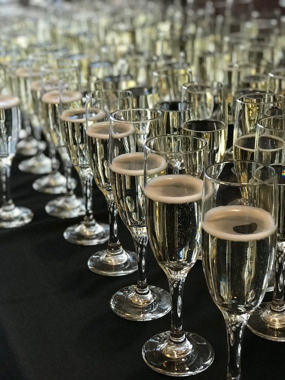 Rows of filled champagne flutes on a black tablecloth