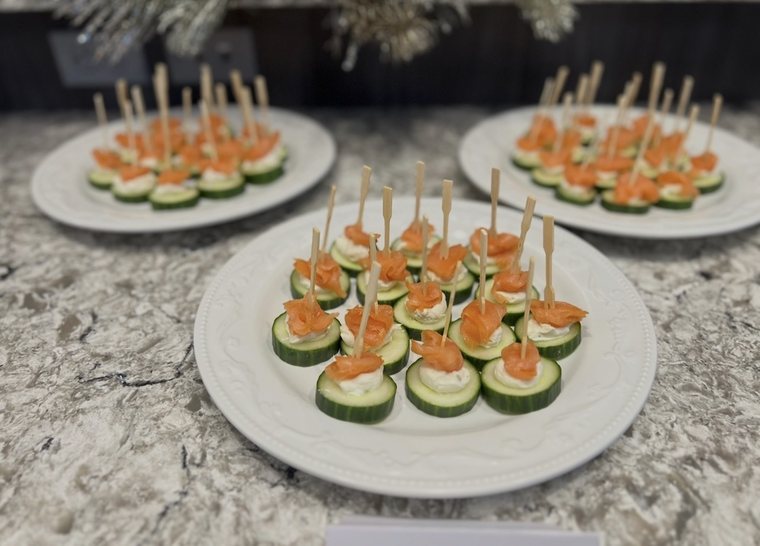 Plates of cucumber rounds topped with herbed cream cheese and smoked salmon on bamboo picks