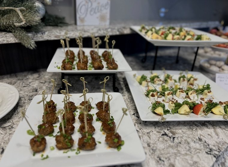 Glazed meatballs on knotted picks beside apple, brie and arugula skewers on tiered white platters