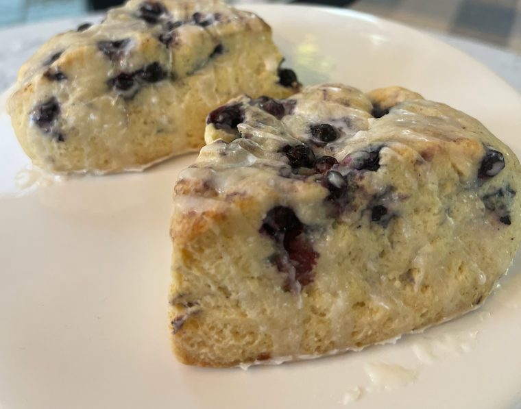 Two glazed blueberry scones on a white plate