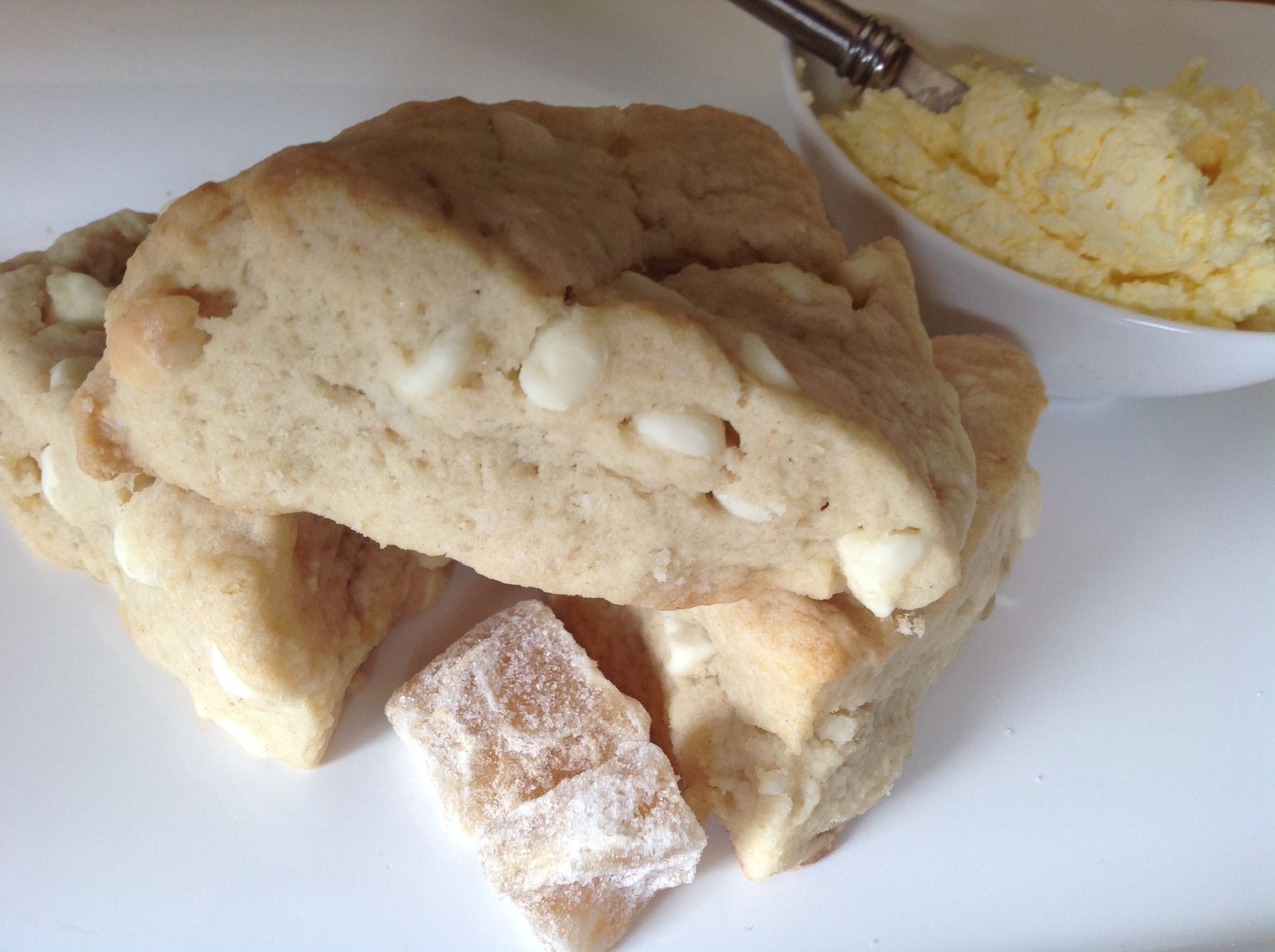 White chocolate candied ginger scones with a dish of cream and pieces of sugared ginger